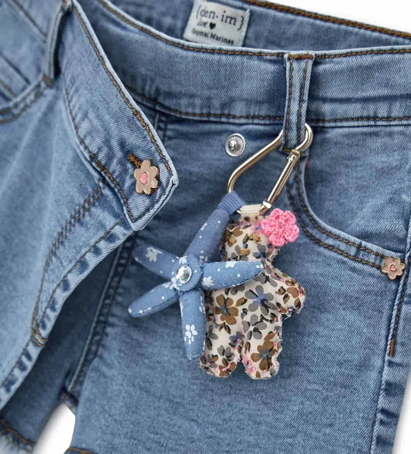 Κοντινό πλάνο στα πριτσίνια σε σχήμα λουλουδιού και τα αφαιρούμενα αξεσουάρ του τζιν σορτς.