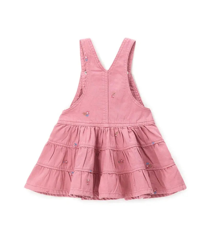 Κοντινό πλάνο στα κεντητά λουλούδια και τις ρυθμιζόμενες τιράντες της παιδικής σαλοπέτας.