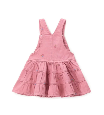 Κοντινό πλάνο στα κεντητά λουλούδια και τις ρυθμιζόμενες τιράντες της παιδικής σαλοπέτας.