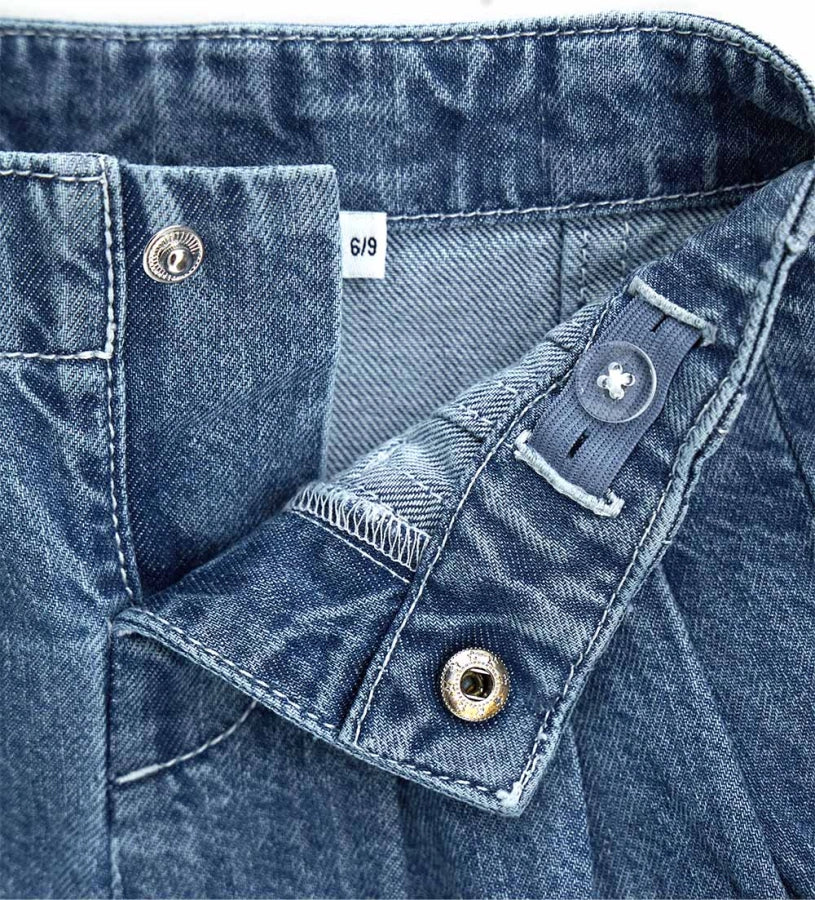 Λεπτομέρεια από το snap button και τη ζώνη faux leather στη βρεφική βερμούδα.