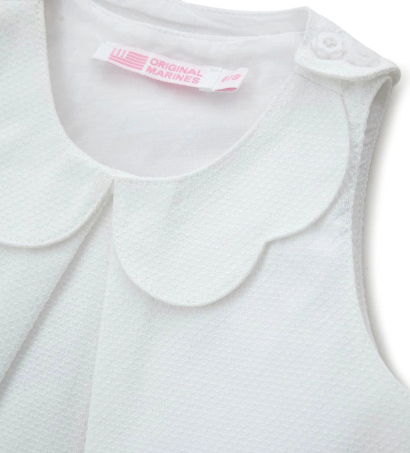 Λεπτομέρεια από το charm στο μπροστινό μέρος και το άνοιγμα στους ώμους της κοριτσίστικης μπλούζας.