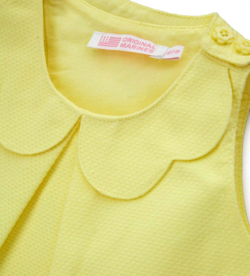 Λεπτομέρεια από το charm στο μπροστινό μέρος και το άνοιγμα στους ώμους της κοριτσίστικης μπλούζας.