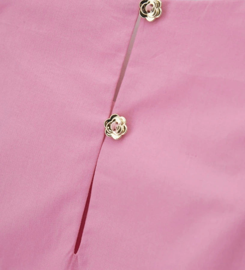 Λεπτομέρεια από τα κουμπιά και τα βολάν στα μανίκια της ροζ παιδικής μπλούζας.