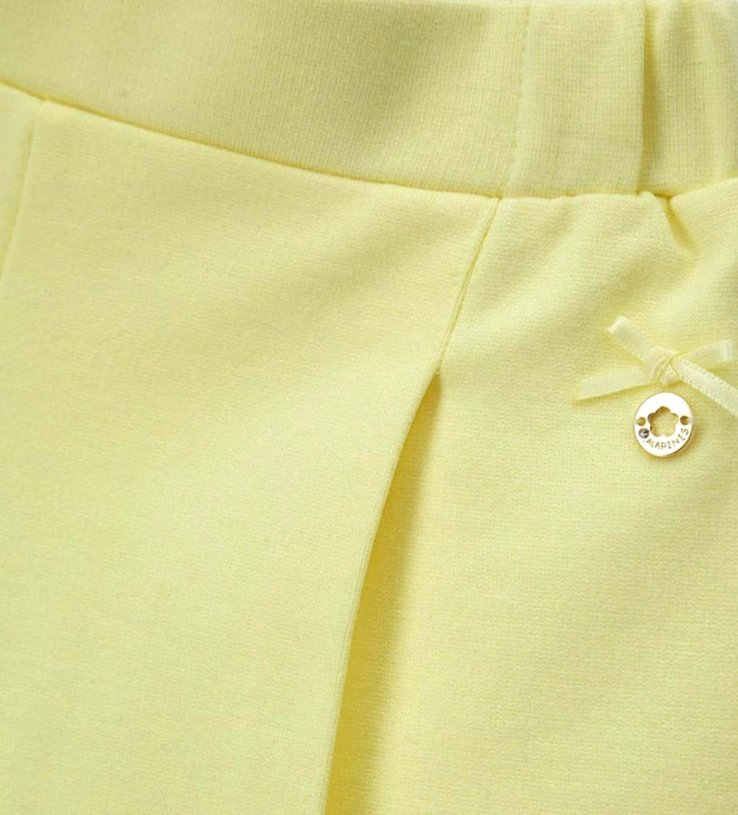 Λεπτομέρεια από τον σατέν φιόγκο και το μεταλλικό charm στην παιδική βερμούδα.