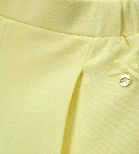 Λεπτομέρεια από τον σατέν φιόγκο και το μεταλλικό charm στην παιδική βερμούδα.