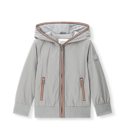 Παιδικό αντιανεμικό μπουφάν για αγόρι σε ανοιχτό γκρι χρώμα με κουκούλα και φερμουάρ.
