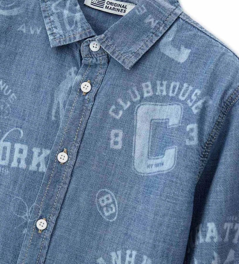 Λεπτομέρεια από την κεντημένη ετικέτα και τα κουμπιά στο αγορίστικο τζιν πουκάμισο.