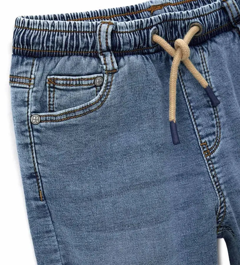 Λεπτομέρεια από το ρυθμιζόμενο κορδόνι και τις τσέπες στο παιδικό denim παντελόνι.