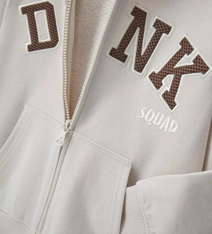 Λεπτομέρεια από την τσέπη καγκουρό και το απλικέ κέντημα στο βαμβακερό φούτερ.