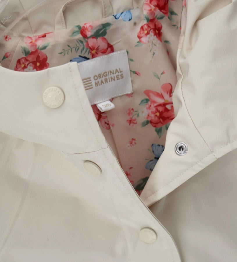 Λεπτομέρεια από την εμπριμέ φόρμα και τα logo snap buttons του κοριτσίστικου μπουφάν.