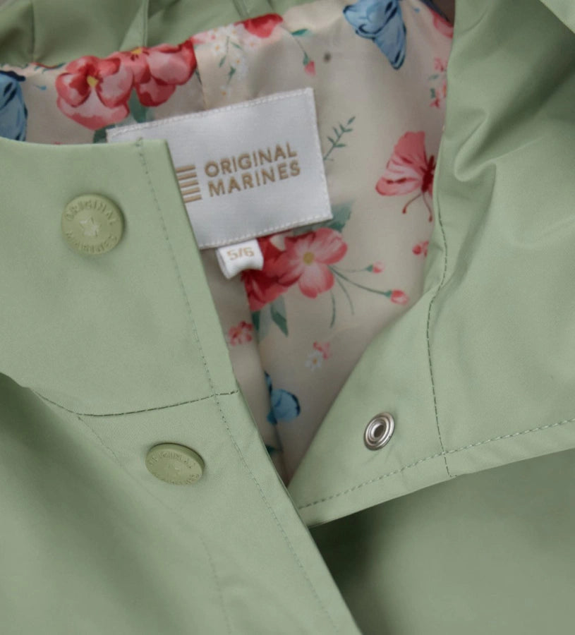 Λεπτομέρεια από την εμπριμέ φόρμα και τα logo snap buttons του κοριτσίστικου μπουφάν.