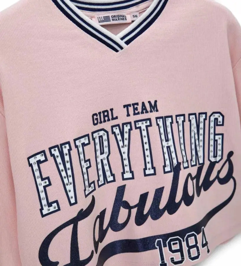 Λεπτομέρεια από τη V λαιμόκοψη και τις ριμπ μανσέτες στο κοριτσίστικο φούτερ.