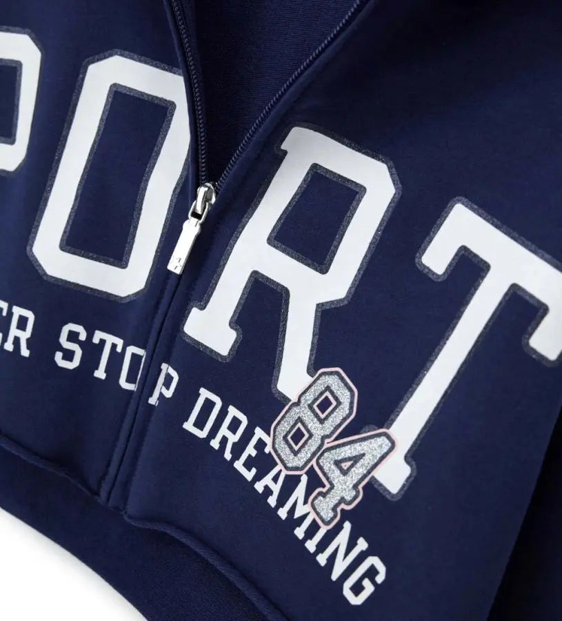 Λεπτομέρεια από το φερμουάρ και το γκλίτερ τύπωμα 84 στην παιδική ζακέτα.