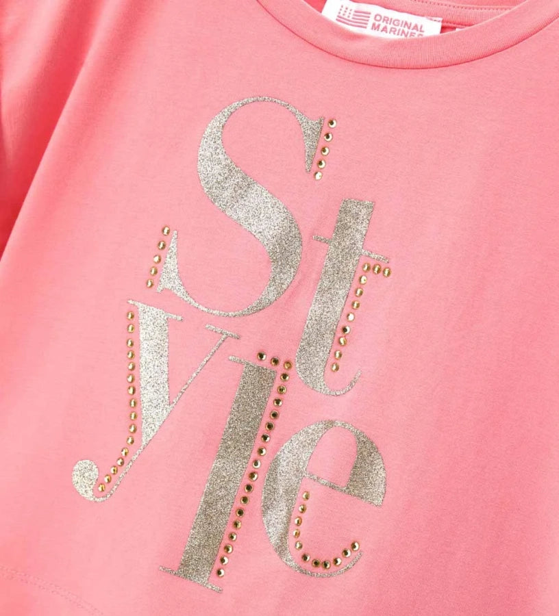 Λεπτομέρεια από το γύρισμα στο μανίκι και τη λάμψη των στρας στο κοριτσίστικο T-shirt.