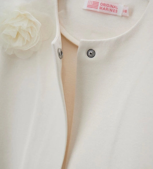 Λεπτομέρεια από το απλικέ λουλούδι από τούλι και το κρυφό κούμπωμα της κοριτσίστικης ζακέτας.