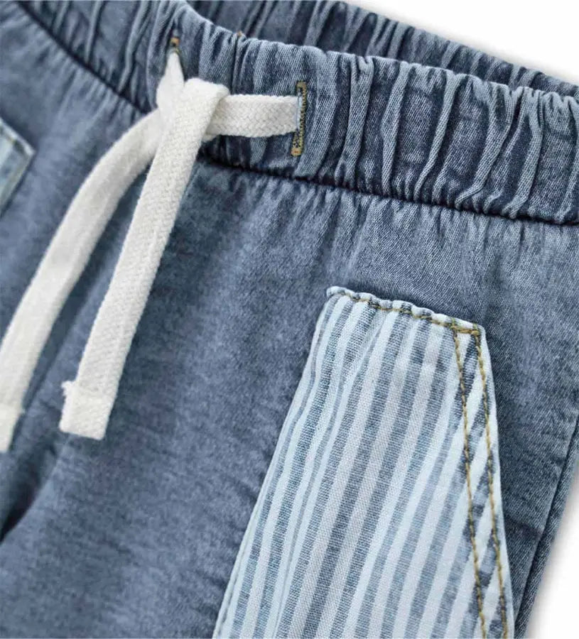 Κοντινό πλάνο στο ρυθμιζόμενο κορδόνι και την ύφανση denim της βρεφικής βερμούδας.