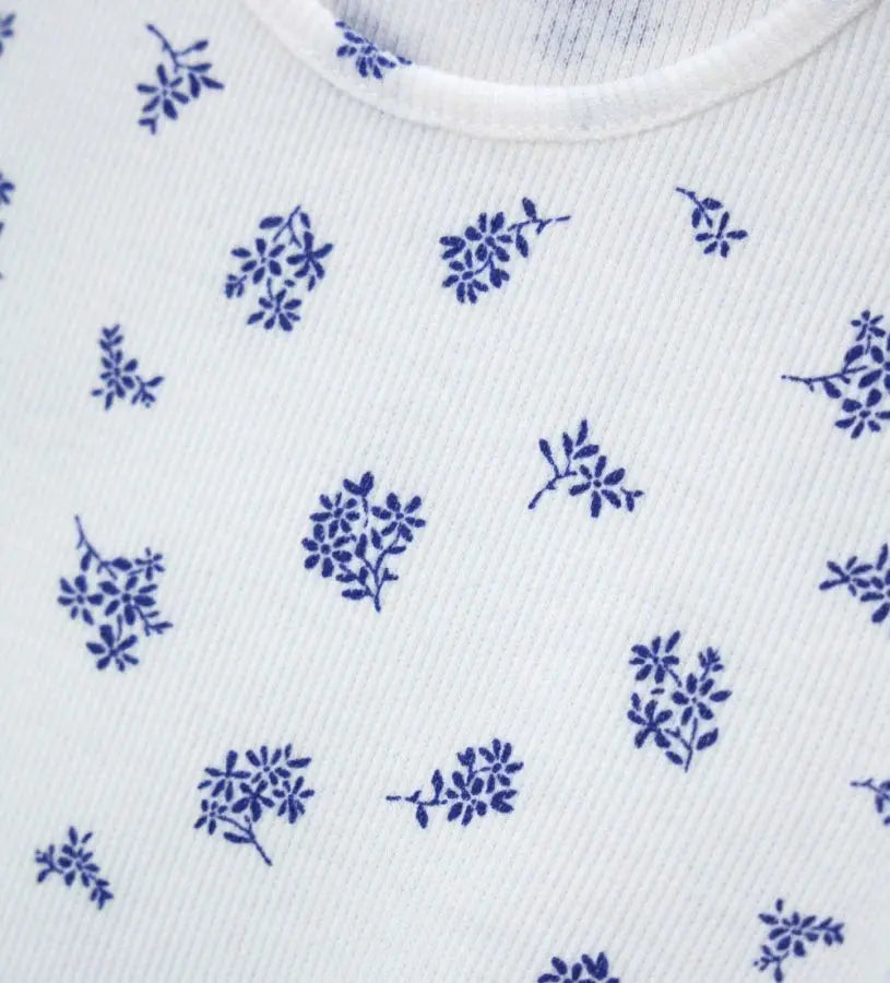 Κοντινό πλάνο στην ανάγλυφη ριμπ ύφανση (costina) και το floral σχέδιο της βρεφικής μπλούζας.